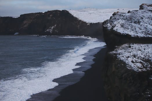 Capture the icy beauty of Vik's iconic black sand beach during winter with dramatic cliffs and waves.
