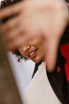 一位微笑的女士，身着夹克，留着非洲式发型，她的特写肖像捕捉了动作与风格