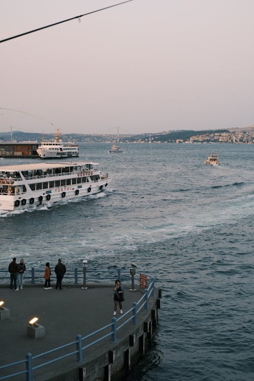 A boat is docked at a pier with people walking on the water