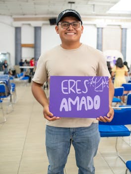 A cheerful man holds a sign reading 'Eres Amado' at a community center in Ciudad de México.