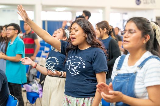 Young adults engaged in worship, expressing joy and unity in a vibrant setting in Ciudad de México.
