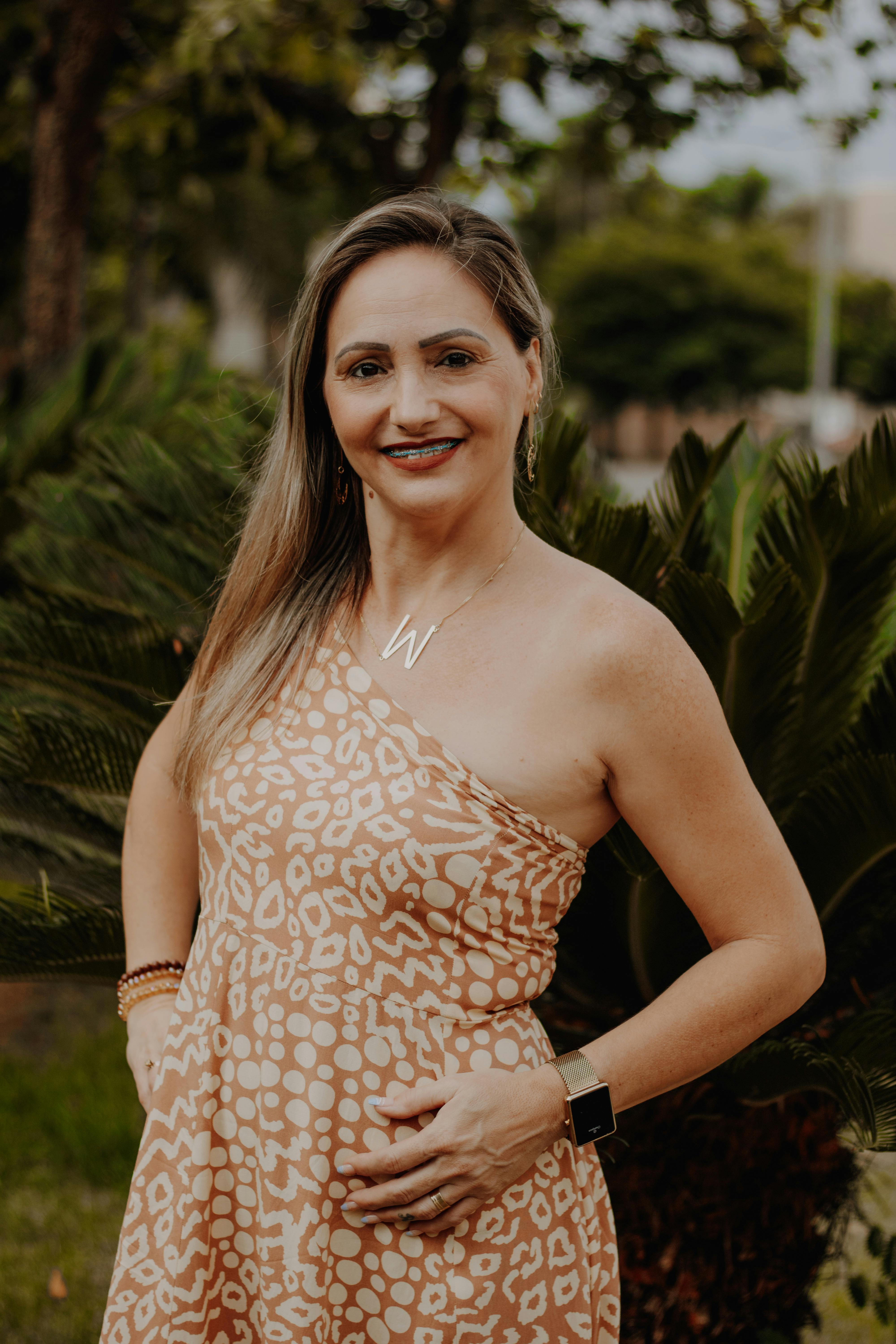 Smiling woman in a patterned dress outdoors, showcasing fashion and confidence.