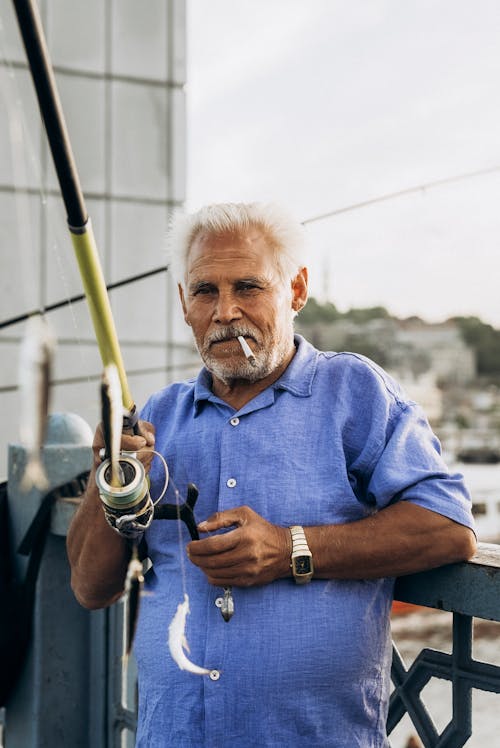 An older man holding a fishing rod and smiling