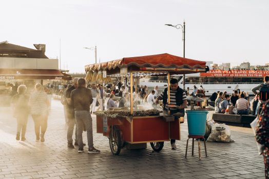 Bustling scene at Galata Bridge with street food vendors and crowds enjoying the sunny Istanbul atmosphere.