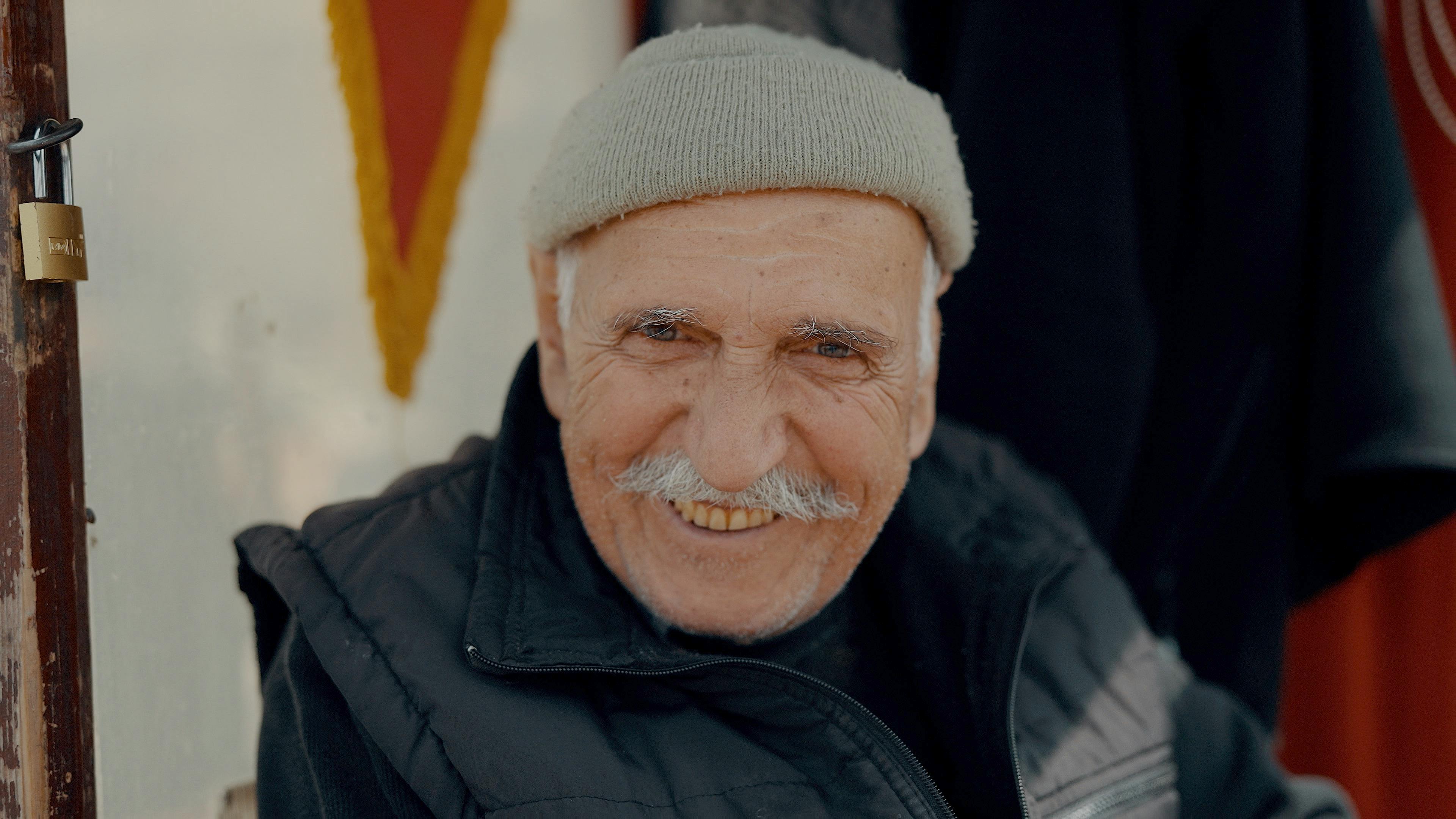 a man with a mustache smiles for the camera