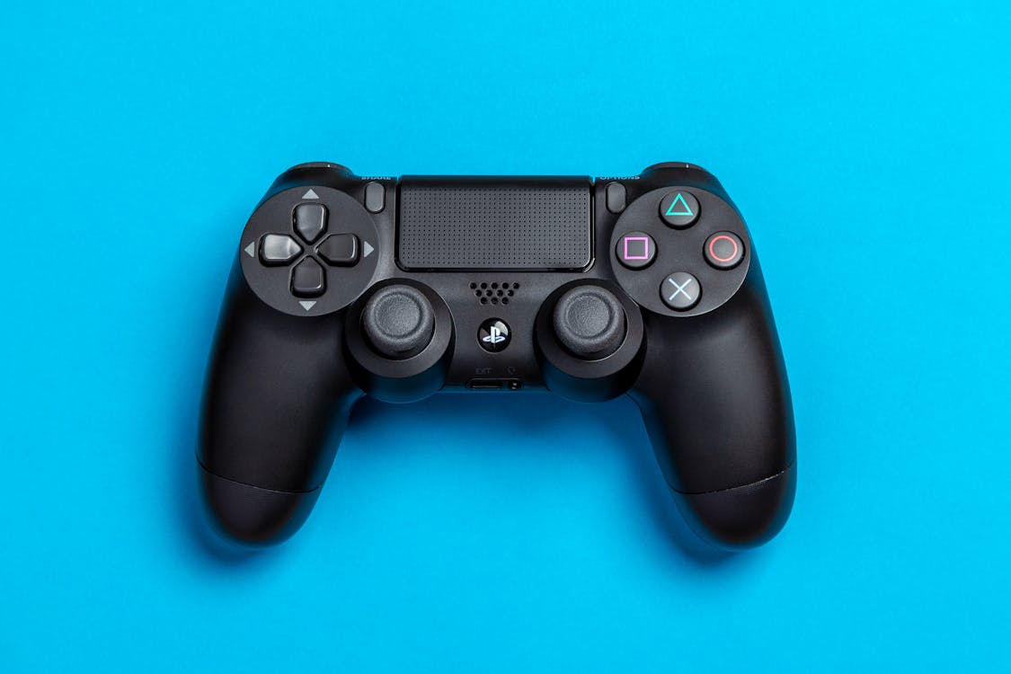 파란색 배경에 검은 색 소니 Ps4 게임 컨트롤러의 평면 배치 사진