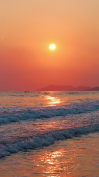 Experience tranquility with a vibrant sunset casting golden hues over gentle ocean waves.
