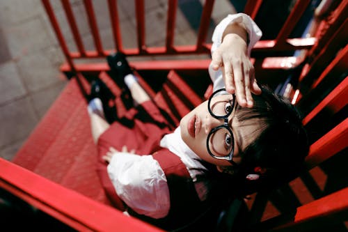 A girl with glasses is sitting on a red stairway