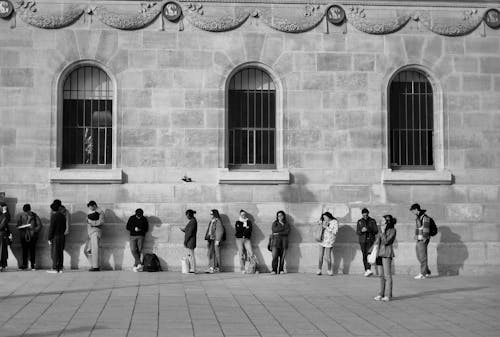 A black and white photo of people waiting in line