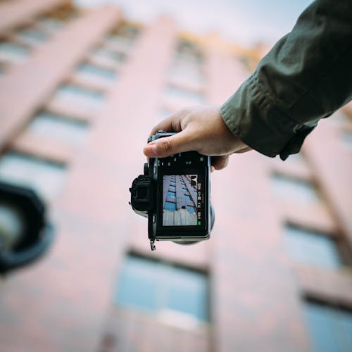 Shallow Focus Photography of Person Holding Black Dslr Camera