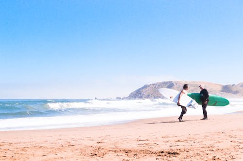 Foto Von Zwei Männern, Die Am Strand Stehen Und Surfbretter Tragen