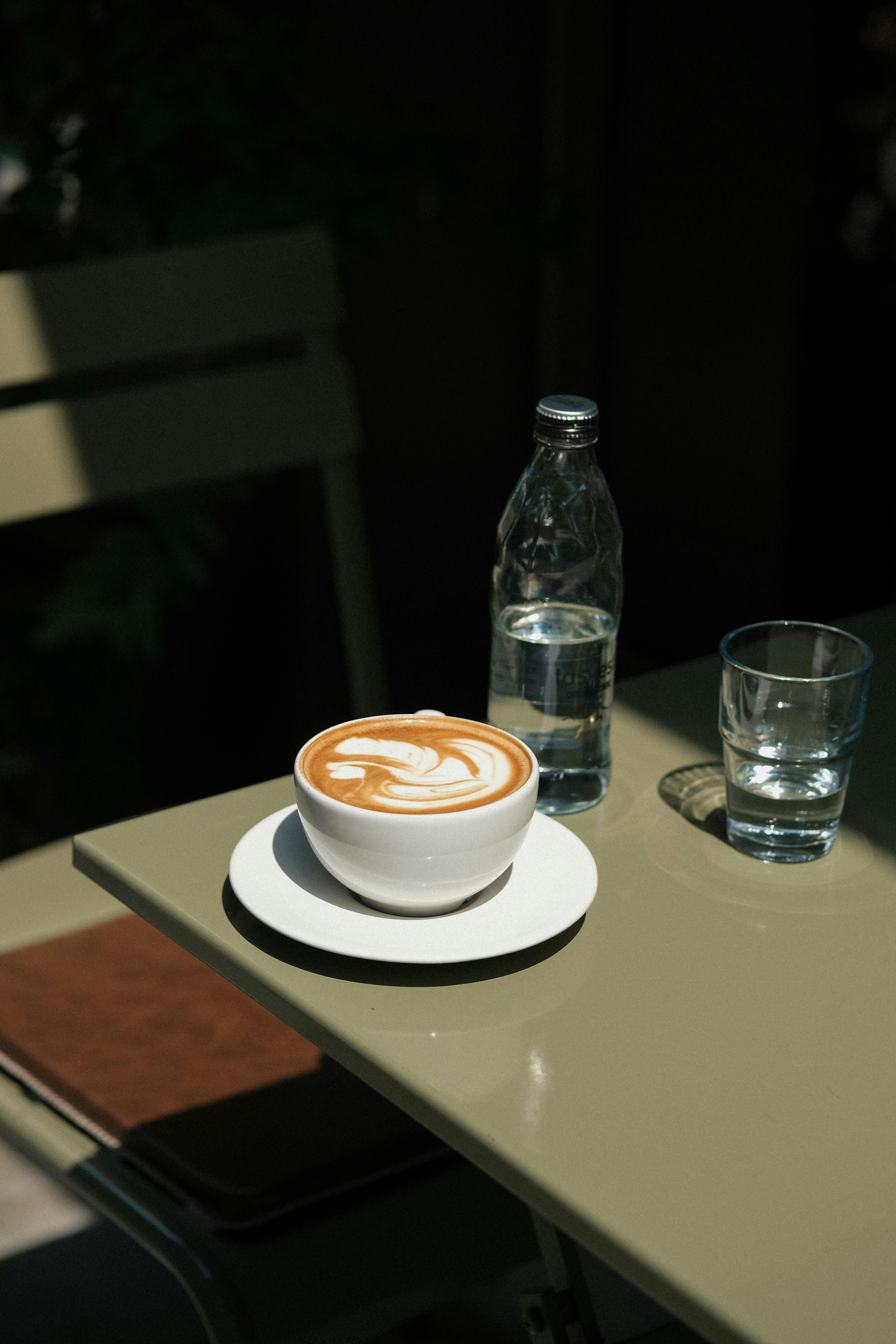 cup of latte and bottle of water on a cafe table