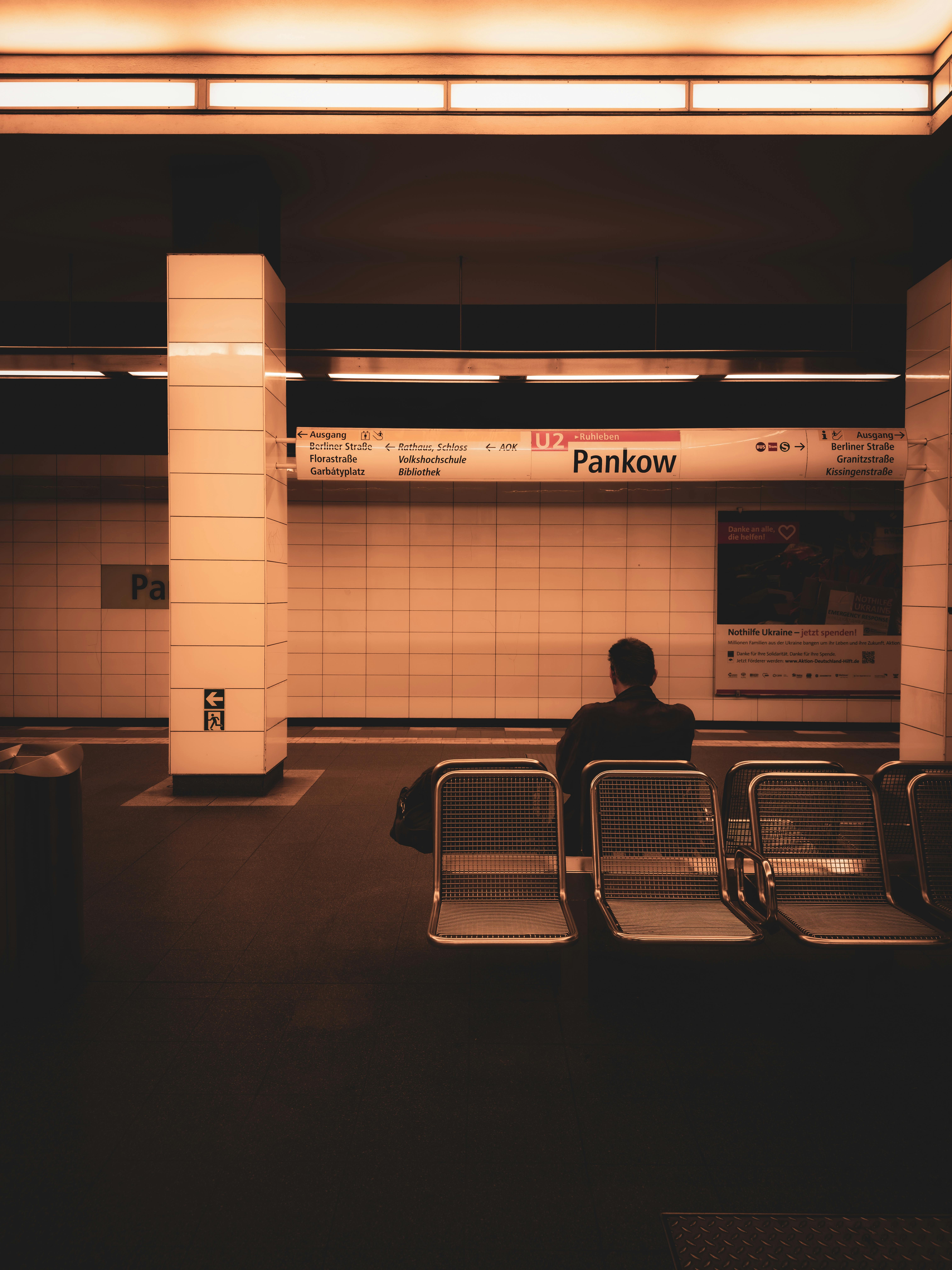 A lone figure sits in Berlin's Pankow U-Bahn station, capturing urban solitude.