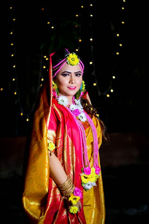 Free Portrait of a woman in colorful traditional Indian clothing with flower accessories, posing elegantly. Stock Photo