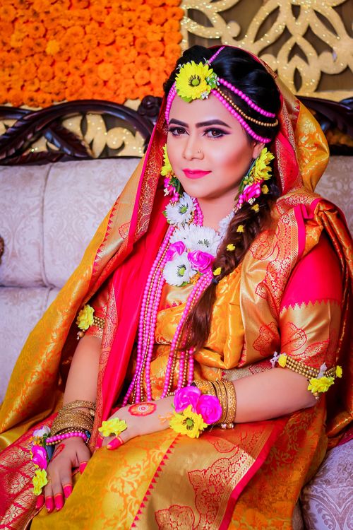 Free A beautiful woman in traditional attire adorned with vibrant floral jewelry, sitting gracefully. Stock Photo