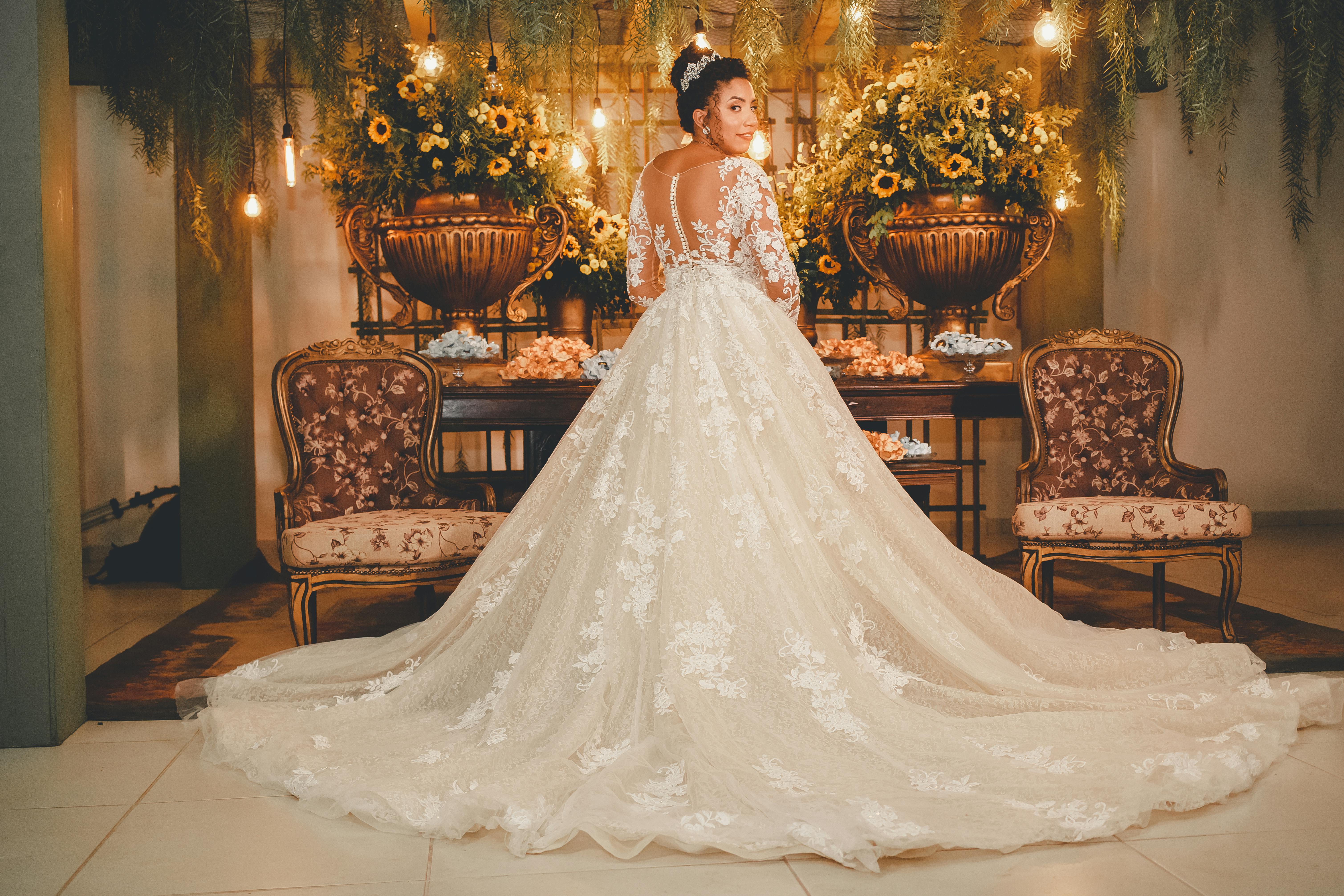 A bride in a lavish wedding dress standing indoors with floral decorations. Perfect for wedding themes.