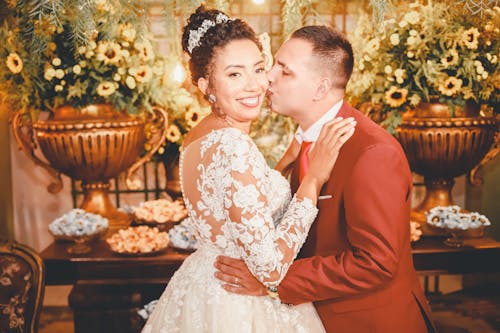 A bride and groom kissing in front of a floral display