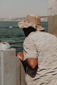 一名戴帽子的男子正享受着俯瞰伊斯坦布尔博斯普鲁斯海峡的宁静时刻