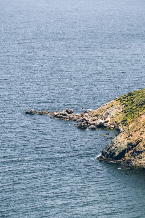 Free Stunning aerial shot of rocky coastline meeting the vast ocean, showcasing natural beauty. Stock Photo