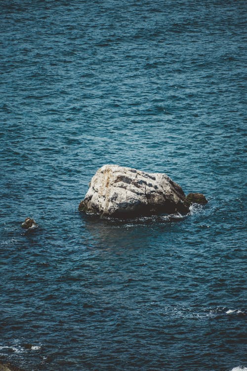A rock in the ocean with a person on it