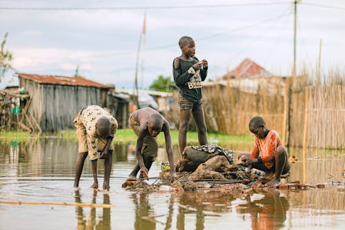 Children playing in a flooded area with a boat