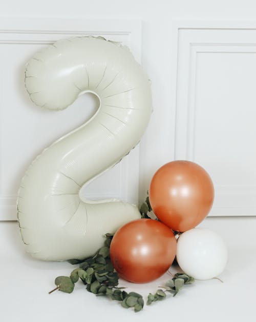 A number two balloon and two green and white balloons