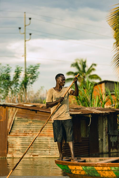 A man is standing on a boat with a pole