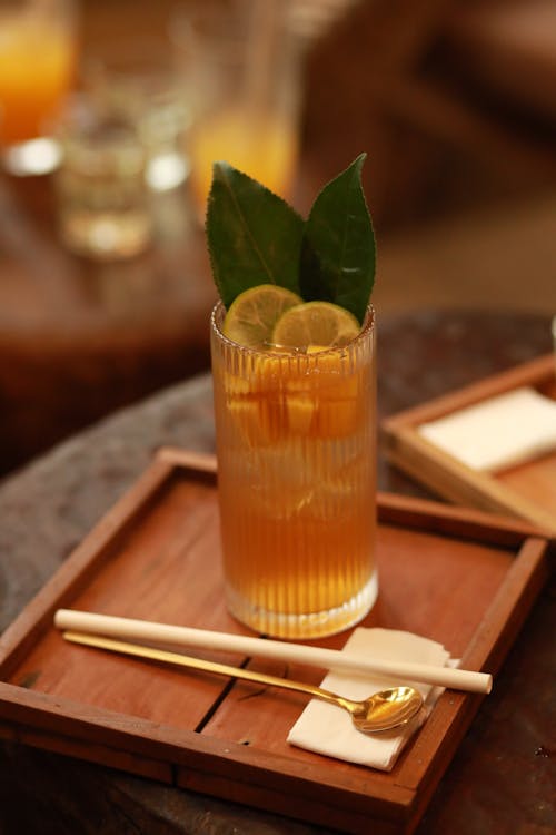 A drink with orange and lemon on a wooden tray