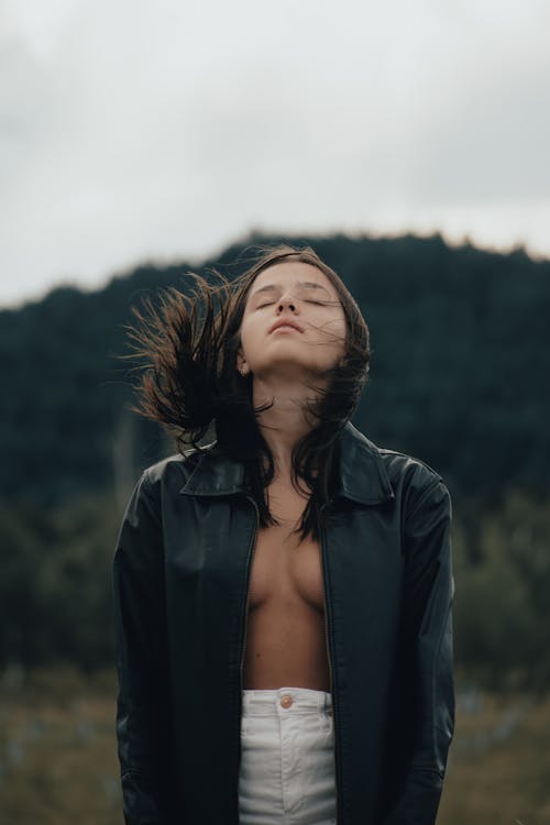 A woman in a black jacket with her hair blowing in the wind