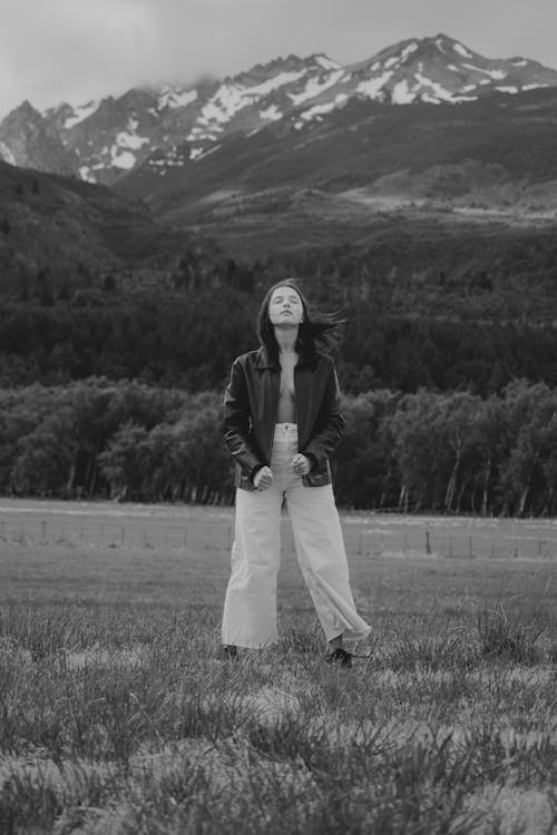 A woman standing in a field with mountains in the background