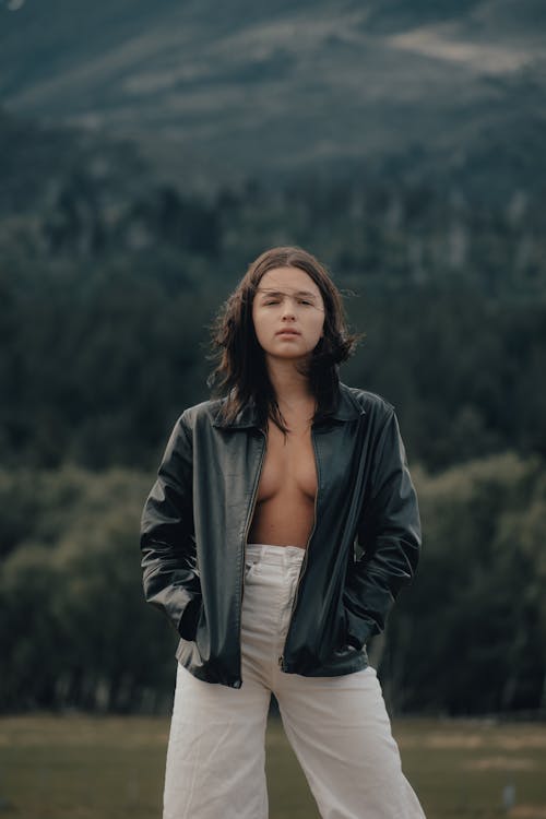 A woman in a leather jacket and white pants