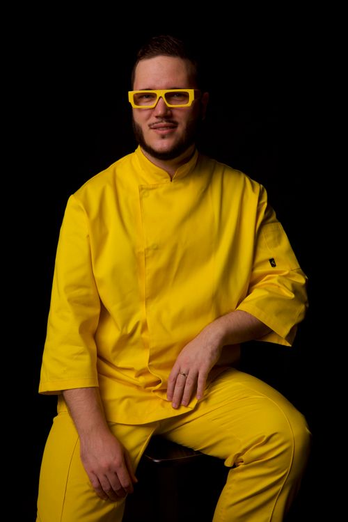 Free A stylish man poses in bright yellow clothing against a black background, showcasing fashion statements. Stock Photo