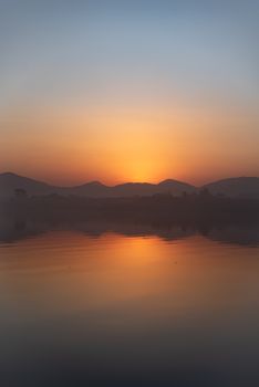 A breathtaking sunset with vibrant gradient sky over a calm lake with perfect reflection. Ideal for nature lovers.