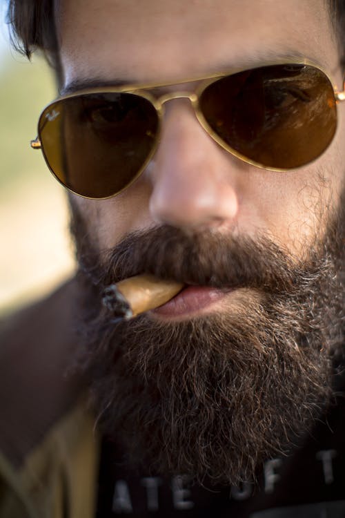 男子吸煙雪茄的特寫照片
