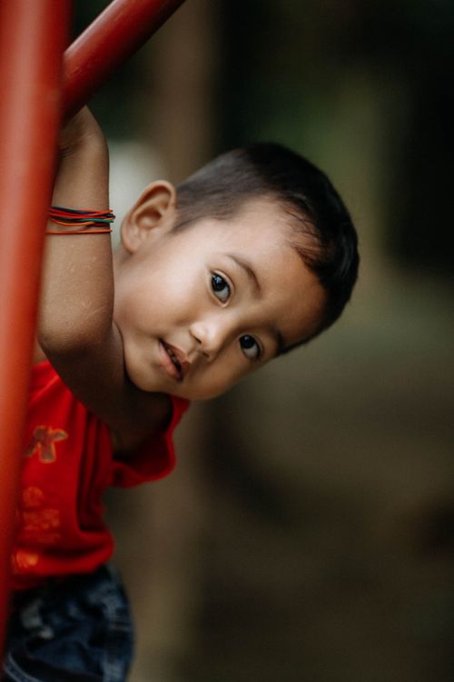 Free Adorable child leaning on colorful playground equipment outdoors. Stock Photo