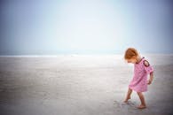 穿着彩色连衣裙的红发年轻女孩在广阔而空旷的海滩上享受着安静的一天