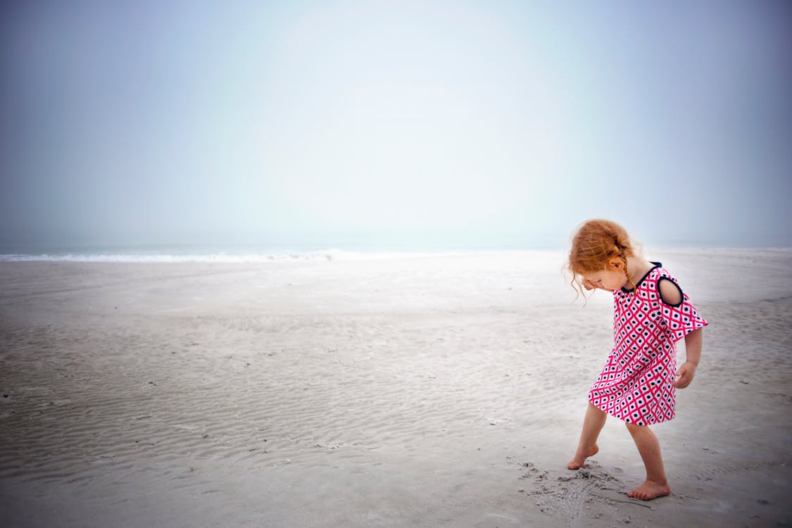 무료 낮 시간 동안 바다 근처 모래에 노는 소녀 스톡 사진