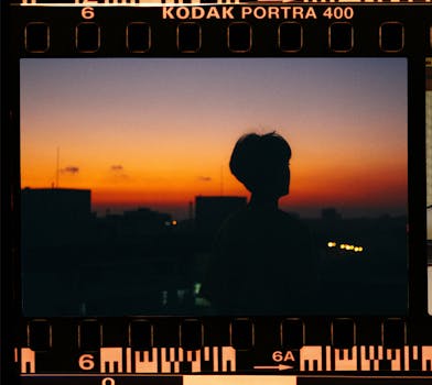 Silhouette of a person against a vibrant sunset, captured on Kodak Portra 400 filmstrip.