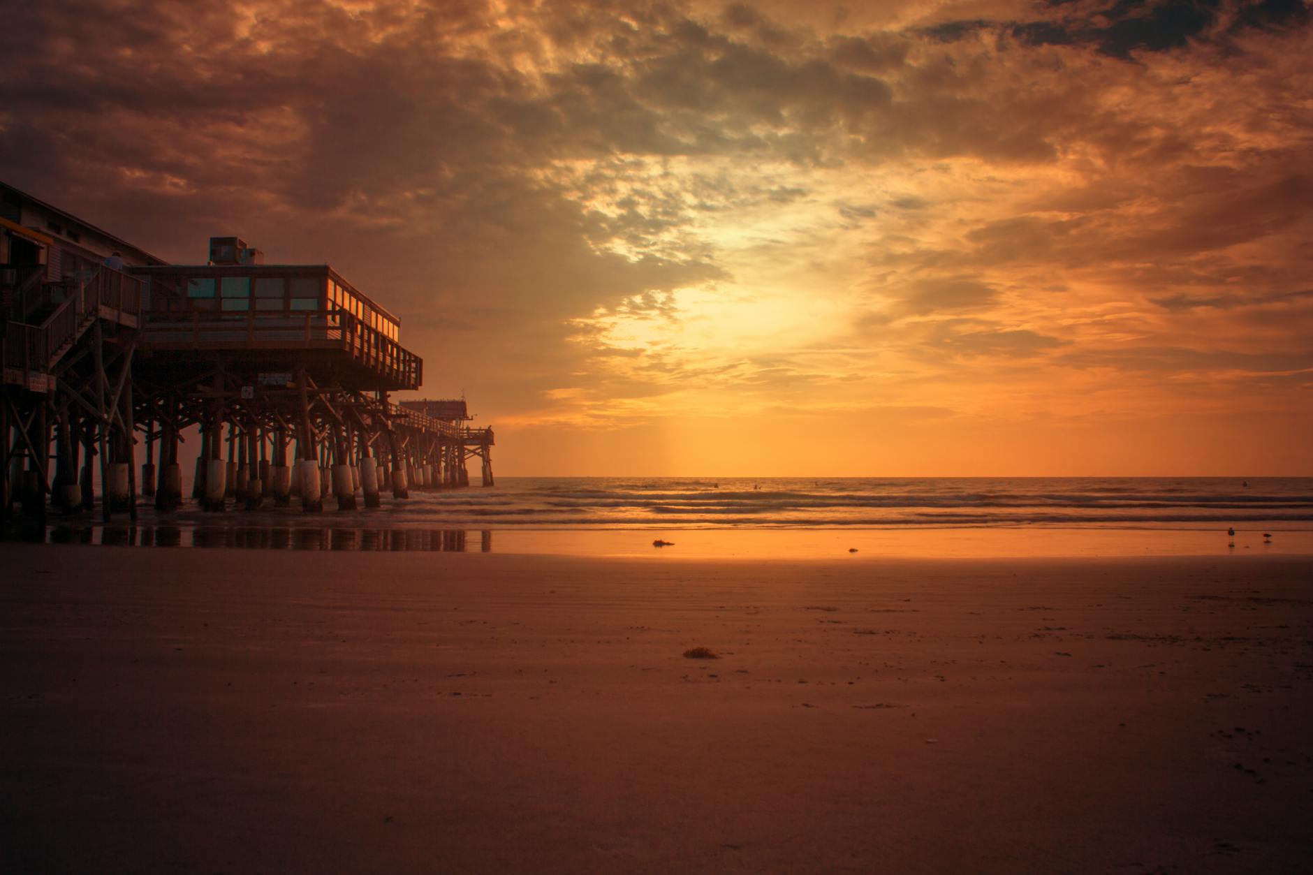 Stunning sunset view of Cocoa Beach Pier, Florida, with a vibrant sky and calm ocean.