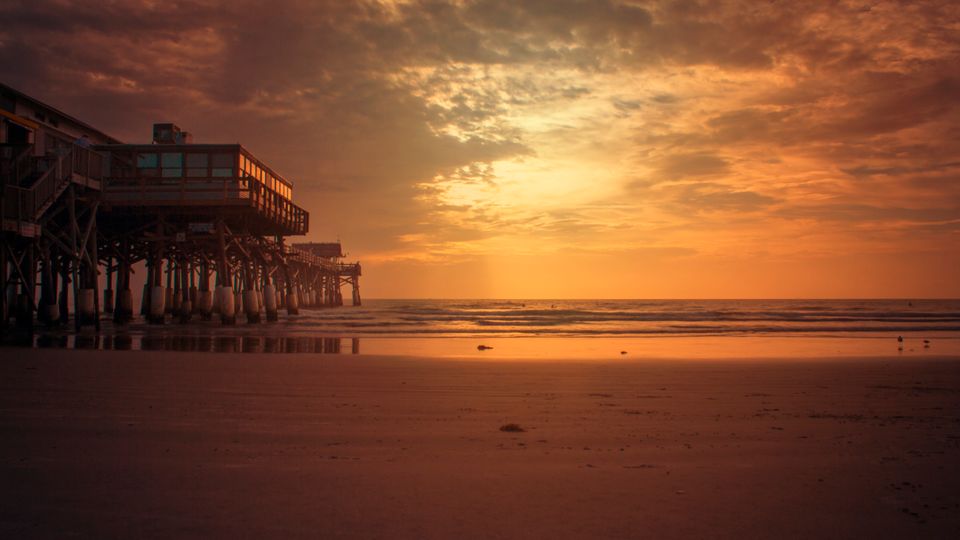 Stunning sunset view of Cocoa Beach Pier, Florida, with a vibrant sky and calm ocean.