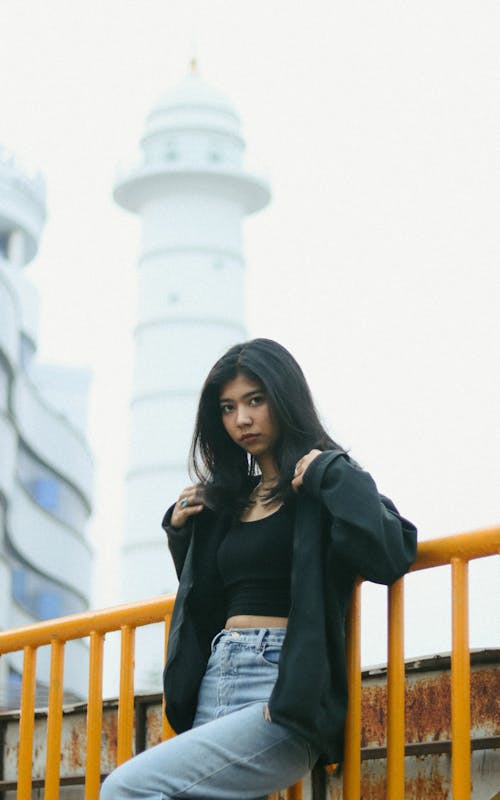 A woman in jeans and a black top posing on a railing