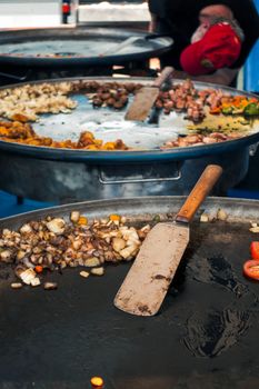 Large frying pans with assorted food at a street market in Lahti, Finland.