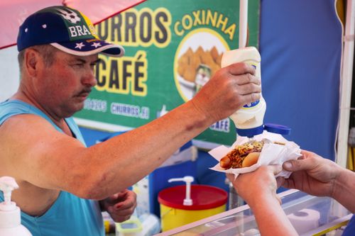 Free Street vendor in Lahti adding toppings to a hot dog for a customer at an outdoor market. Stock Photo
