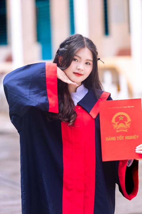 A woman in a graduation gown holding up a book