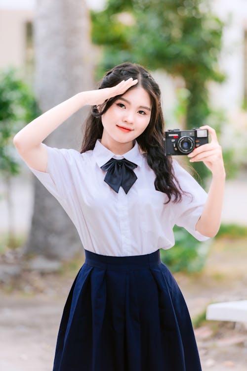 A girl in a school uniform taking a photo