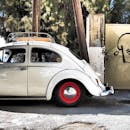 一辆经典白色大众甲壳虫停在城市街道上，轮子是红色的