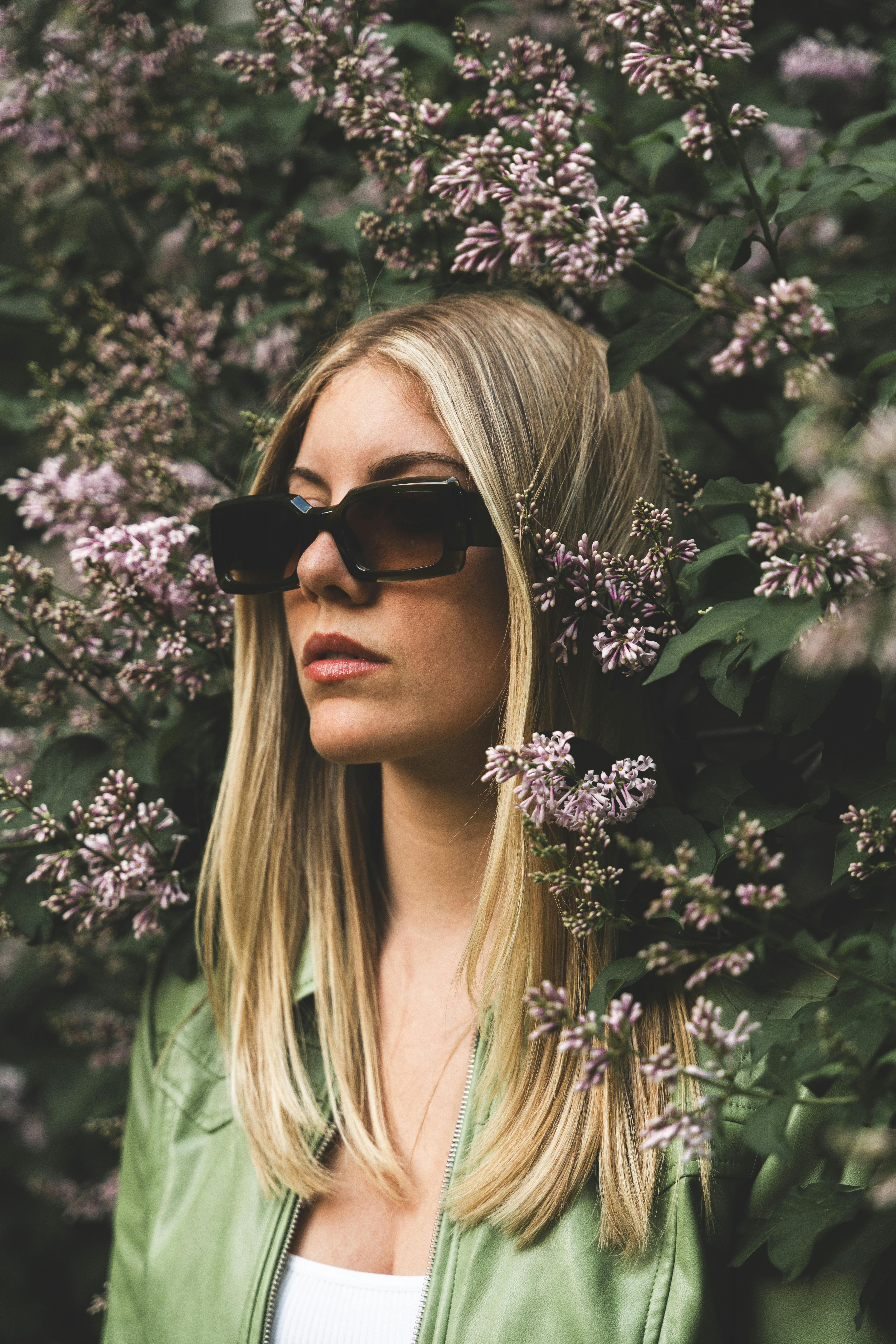 Portrait of a blonde model in sunglasses surrounded by lilac flowers in Montréal.