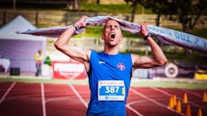 运动员在马拉松终点线举起胶带，胜利地庆祝胜利