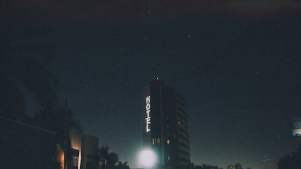 Low angle shot of a hotel with neon signage at night, creating a moody urban atmosphere.