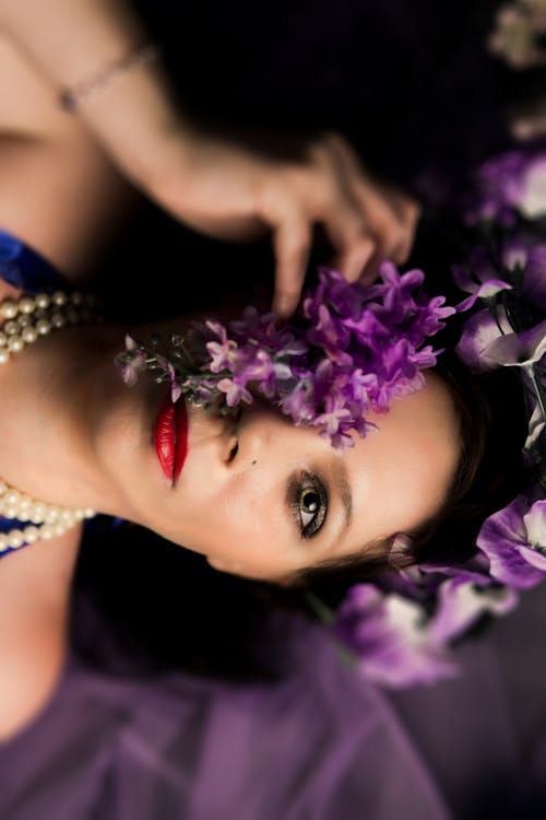 Fotografia De Mulher Deitada, Cobrindo Os Olhos Com Flores De Pétalas Roxas